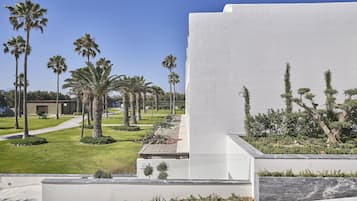 A modern building with a flat roof, surrounded by a well-maintained lawn and palm trees.