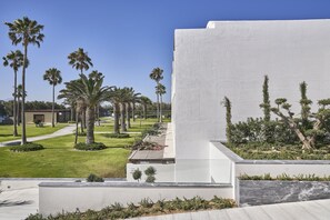 Un bâtiment moderne doté d’un toit plat, entouré d’une pelouse bien entretenue et de palmiers.