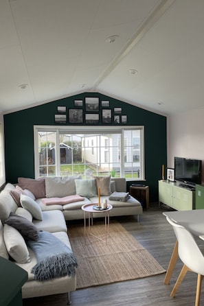 A modern living room with a large window, a sofa, a coffee table, and a television. - RBR 711 - Beach Resort Kamperland by Interhome (Kamperland)