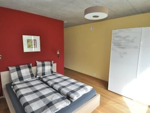 Une chambre à coucher avec un lit, un mur rouge, un mur jaune et une armoire blanche.