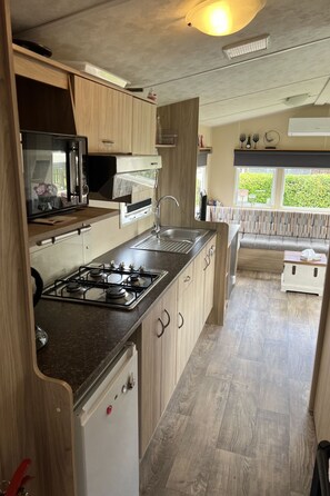 A compact kitchen with a gas stove, a microwave, and a sink. - RBR 166 - Beach Resort Kamperland by Interhome (Kamperland)