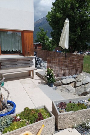 Eine Terrasse mit Sitzgelegenheit im Freien, einem Holzzaun und einem Blumentopf.