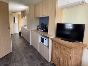 A modern kitchen with wooden cabinets, a built-in dishwasher, a coffee maker, and a flat-screen TV on a wooden cabinet. - RBR 1252 - Beach Resort Kamperland by Interhome (Kamperland)