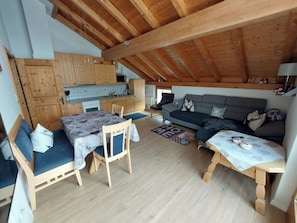 Ein gemütliches Loft mit Esstisch, Sofa und Küchenzeile.