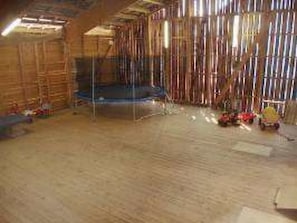 Ein Innenraum mit Trampolin, Holzboden und verstreuten Spielzeugen.