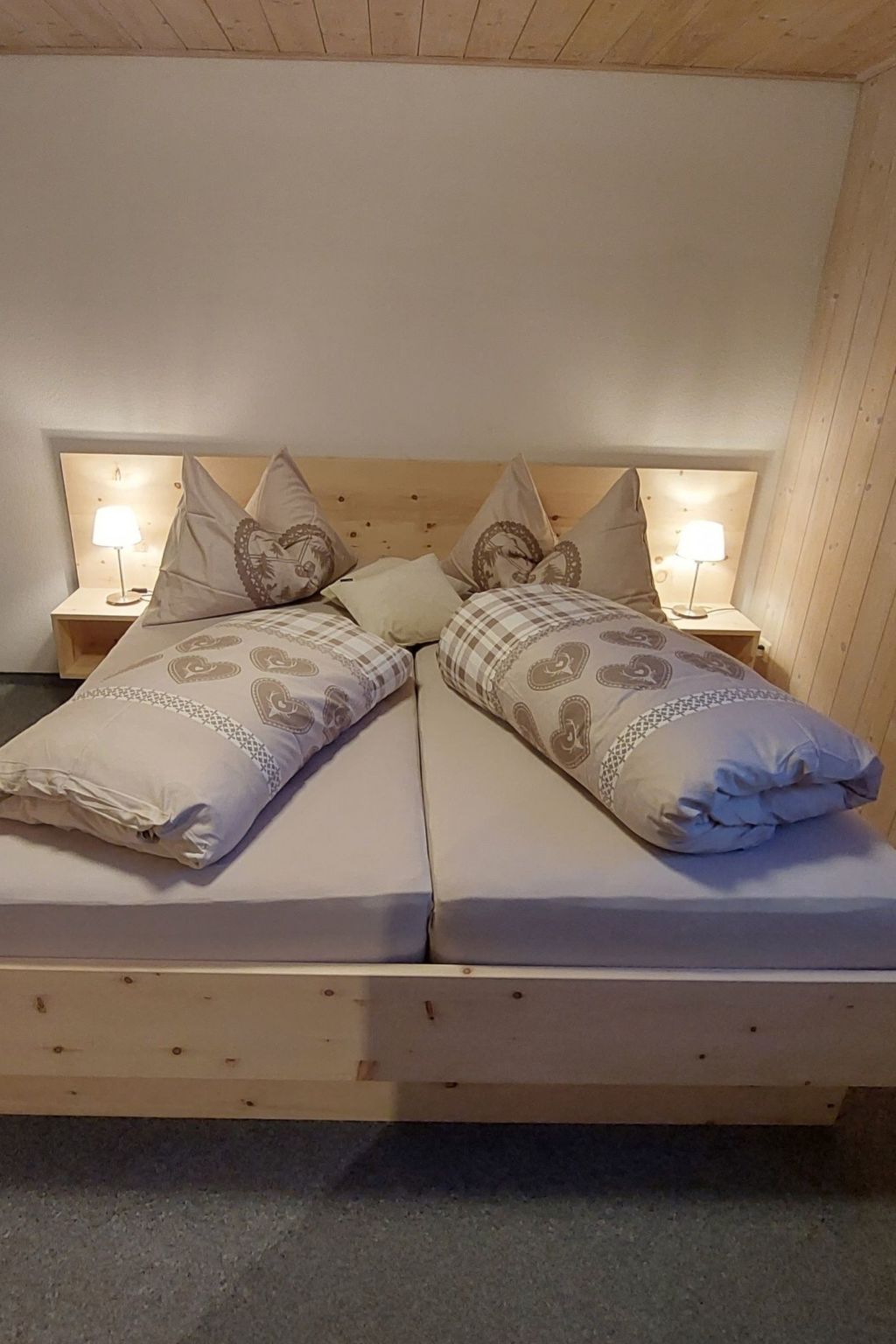 Een tweepersoonsbed met gestreepte kussens en twee bedlampjes.