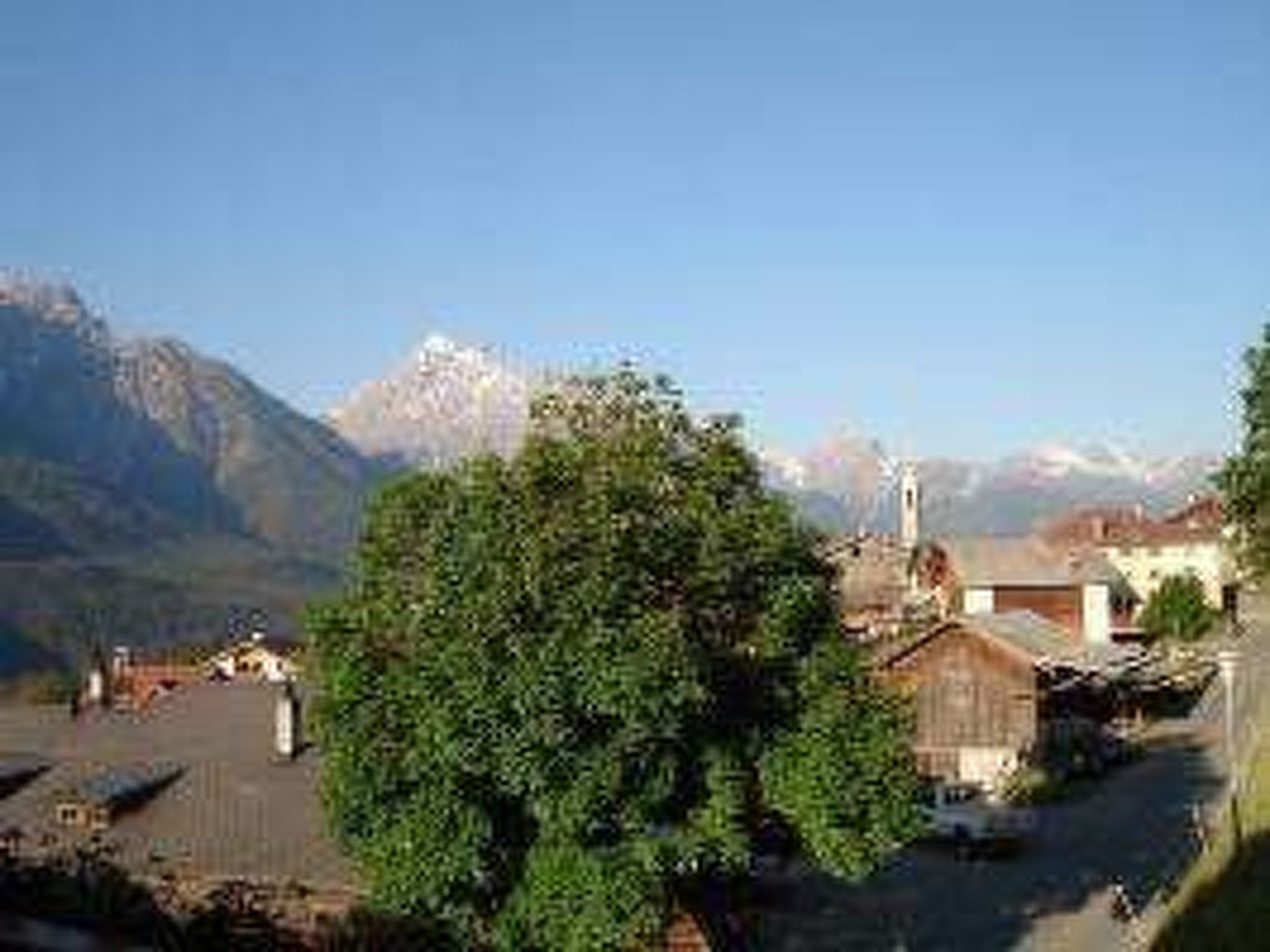 Un village de montagne aux bâtiments traditionnels, avec une église et une vue dégagée sur les montagnes environnantes.