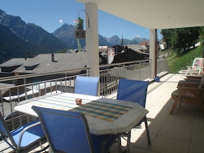 Une terrasse avec une table et des chaises, offrant une vue sur un paysage montagneux.