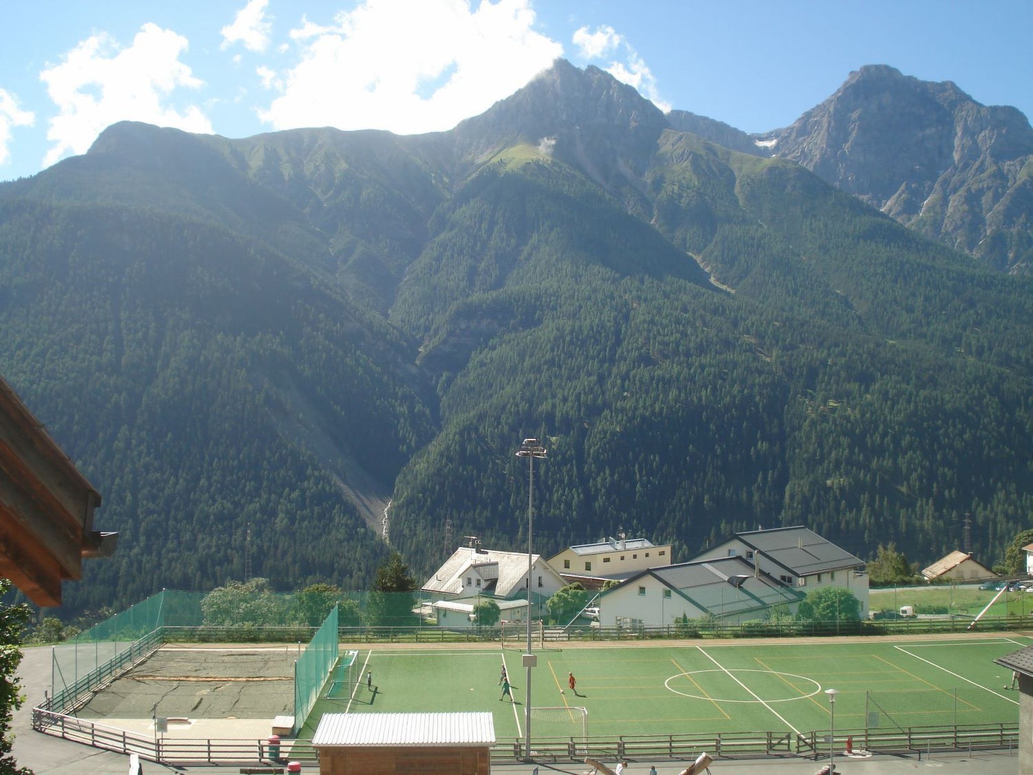 Un terrain de sport avec une chaîne de montagnes en arrière-plan, entouré de bâtiments.