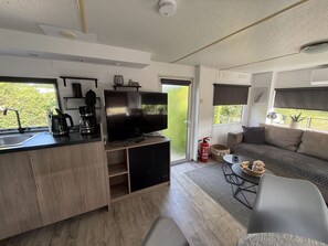 A compact living space with a kitchenette, a flat-screen TV, a sofa, and a dining area. - RBR 168 - Beach Resort Kamperland by Interhome (Kamperland)