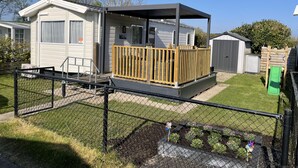 A mobile home with a fenced yard, a small deck, and a shed. - RBR 1132 - Beach Resort Kamperland by Interhome (Kamperland)