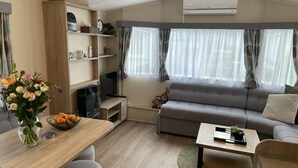 A modern living room with a sofa, TV, and a dining area with a table and chairs. - RBR 1132 - Beach Resort Kamperland by Interhome (Kamperland)