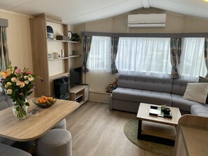 A modern living room with a sofa, TV, and a dining area with a table and chairs. - RBR 1132 - Beach Resort Kamperland by Interhome (Kamperland)
