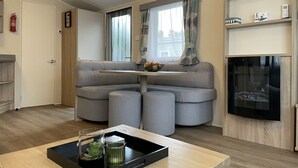 A modern living room with a sofa, a small table with a tray, a fireplace, and a television. - RBR 1132 - Beach Resort Kamperland by Interhome (Kamperland)