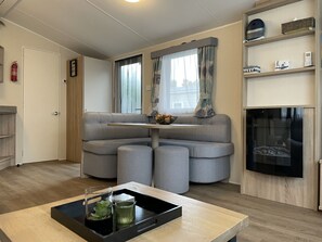 A modern living room with a sofa, a small table with a tray, a fireplace, and a television. - RBR 1132 - Beach Resort Kamperland by Interhome (Kamperland)
