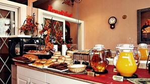 A breakfast buffet with various pastries, a coffee machine, and juice dispensers. - Midtown inn (Baltimore)