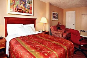 A hotel room with a bed, a desk, a chair, a lamp, and two paintings on the wall. - Midtown inn (Baltimore)