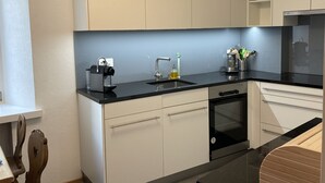 A modern kitchen with white cabinets, a black countertop, and a built-in dishwasher.