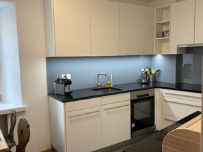A modern kitchen with white cabinets, a black countertop, and a built-in dishwasher.