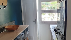 Eine moderne Küche mit einem Holzespeisetisch, Stühlen, einem großen Fenster und einem eingebauten Backofen.