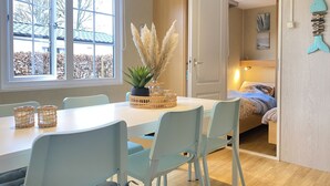 A dining area with a table, chairs, and a window with a view of trees. - Rbr 813 - Beach Resort Kamperland by Interhome (Kamperland)