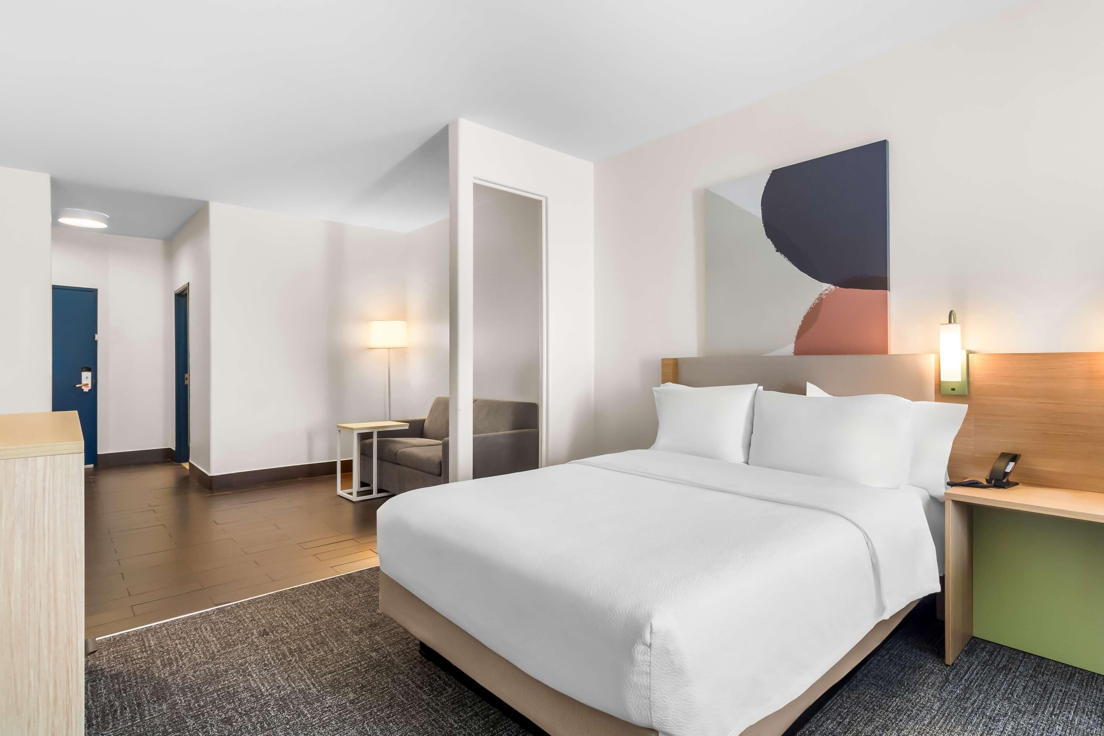 Ein Hotelzimmer mit einem großen Bett, einem Schreibtisch, einem Stuhl und einer Wandlampe.