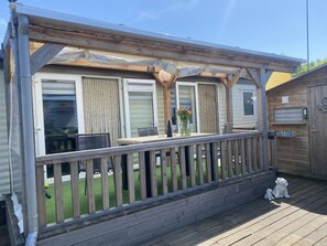 A covered outdoor deck with a wooden railing, a table, chairs, and a small dog statue. - RBR 232 - Beach Resort Kamperland by Interhome (Kamperland)