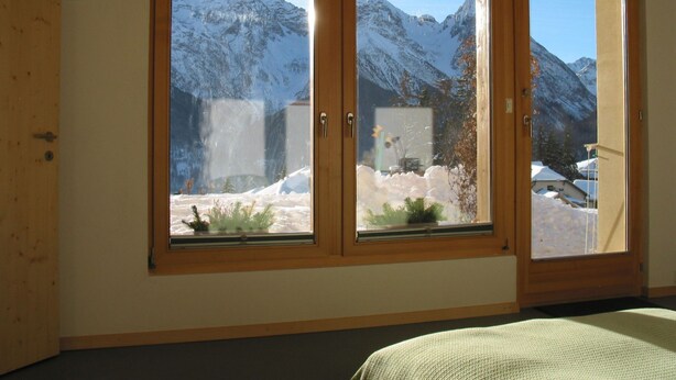 Een kamer met een groot raam dat uitzicht biedt op met sneeuw bedekte bergen.