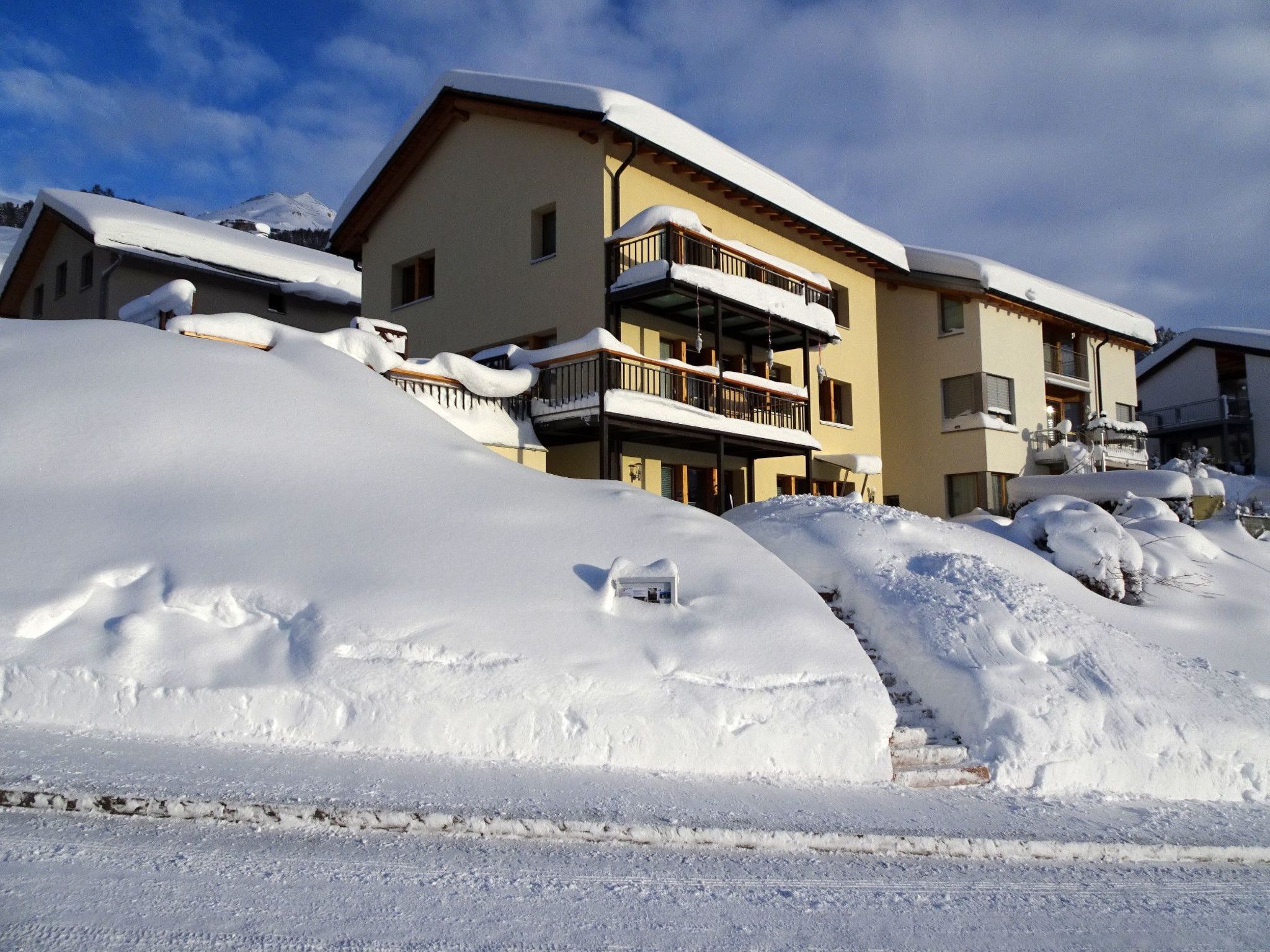 Un edificio de varios pisos con balcones cubiertos de nieve, rodeado de terreno nevado.
