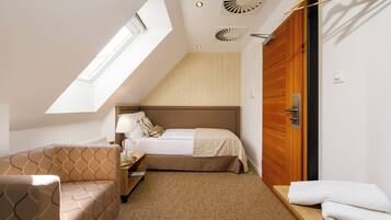 Un dormitorio con cama, sofá, mesita de noche, lámpara, ventana y puerta de madera.