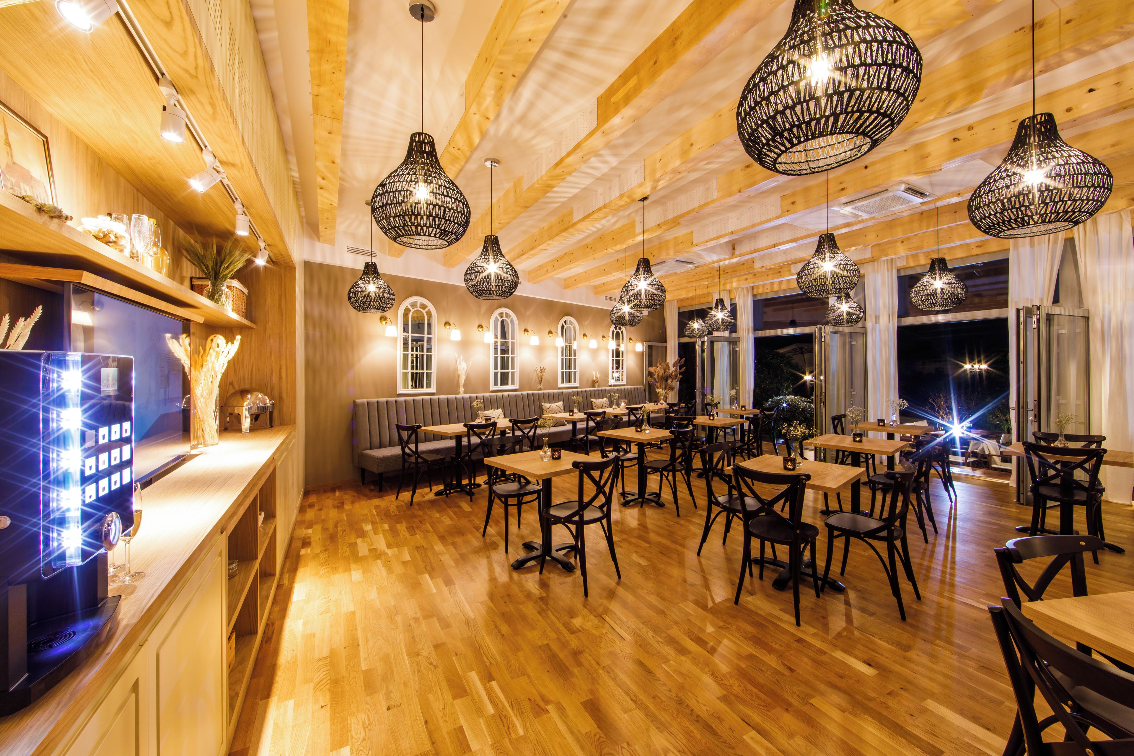 Een restaurant met houten vloeren, zwarte hanglampen en een bar.