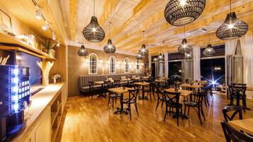 Een restaurant met houten vloeren, zwarte hanglampen en een bar.