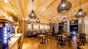 Un restaurante con pisos de madera, candelabros negros colgantes y una zona de bar.