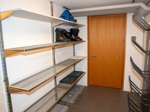 Una zona d'emmagatzematge amb prestatges metàl·lics, una porta de fusta i un sòl de rajola.