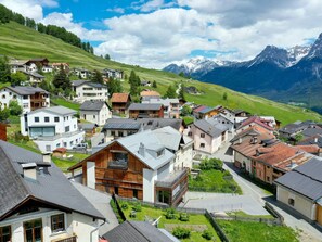 A mountain village with traditional and modern houses, a clear sky, and snow-capped mountains in the background. - Chasa Flora, (Ftan) by Interhome (Ftan)