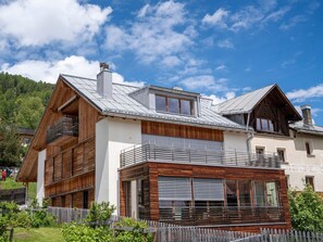 A modern two-story house with a wooden facade, large windows, and a balcony. - Chasa Flora, (Ftan) by Interhome (Ftan)
