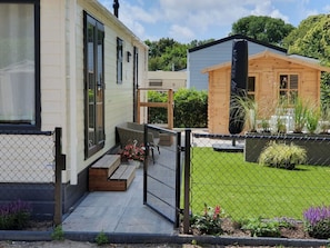 Un immobile residenziale con patio coperto, cortile recintato e una piccola struttura in legno.