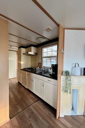 Eine moderne Küche mit Holzboden, einem eingebauten Herd, einem Fenster und einem weißen Schrank.