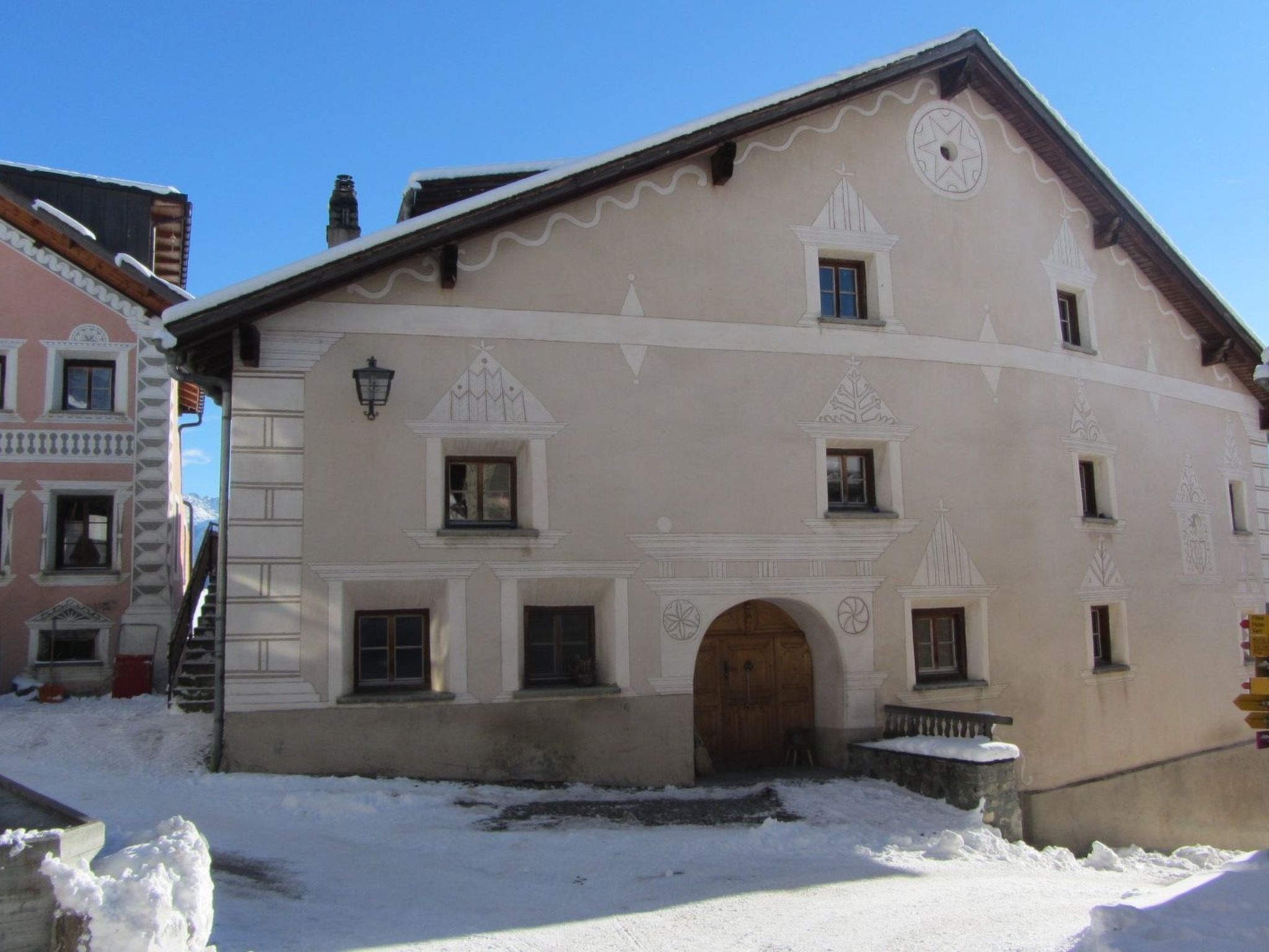 Ein Gebäude mit einer symmetrischen Fassade, zahlreichen Fenstern und einem zentralen Rundbogenportal.