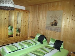 A wooden-paneled room with a bed, a mirror, and a wall-mounted decoration. - Chasa Cumulus/HP Ferienwohnung Sainas 139 A, (Ftan) by Interhome (Ftan)