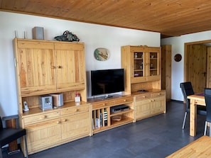 A wooden entertainment unit with a flat-screen TV, storage cabinets, and a small table with chairs. - Chasa Cumulus/HP Ferienwohnung Sainas 139 A, (Ftan) by Interhome (Ftan)