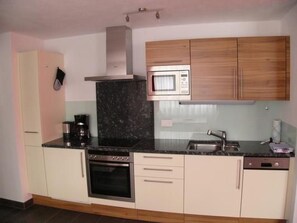 A kitchen with a stove, oven, microwave, and a sink. - Chasa Percosta, (Scuol) by Interhome (Scuol)