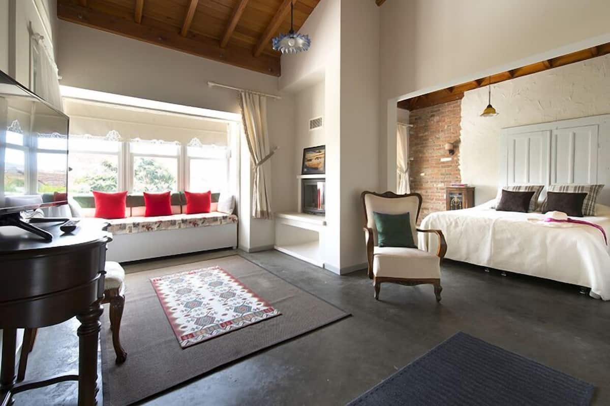 A bedroom with a bed, a chair, a desk, and a window with curtains.