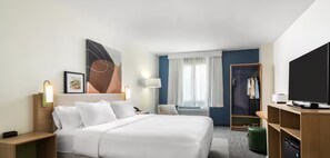 Una habitación de hotel con cama, televisión, armario y escritorio.