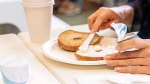 Una persona untando mantequilla en una rebanada de pan sobre un plato.