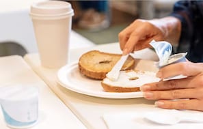 Una persona untando mantequilla en una rebanada de pan sobre un plato.