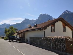 Een huis met een schuin dak, een garage en uitzicht op bergen.