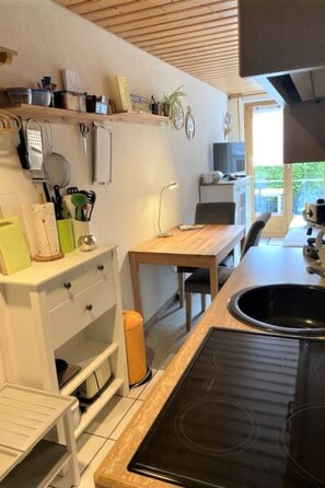 Een keuken met een aanrecht, spoelbak en fornuis. Er is een raam dat voor natuurlijk licht zorgt.