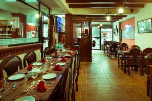 A restaurant with a long dining table set for a meal, chairs, and a bar area in the background. - Kathmandu Eco (Kathmandu)