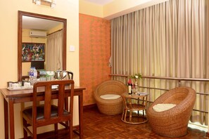 A room with a dining table, two wicker chairs, a small side table, and a large mirror. - Kathmandu Eco (Kathmandu)